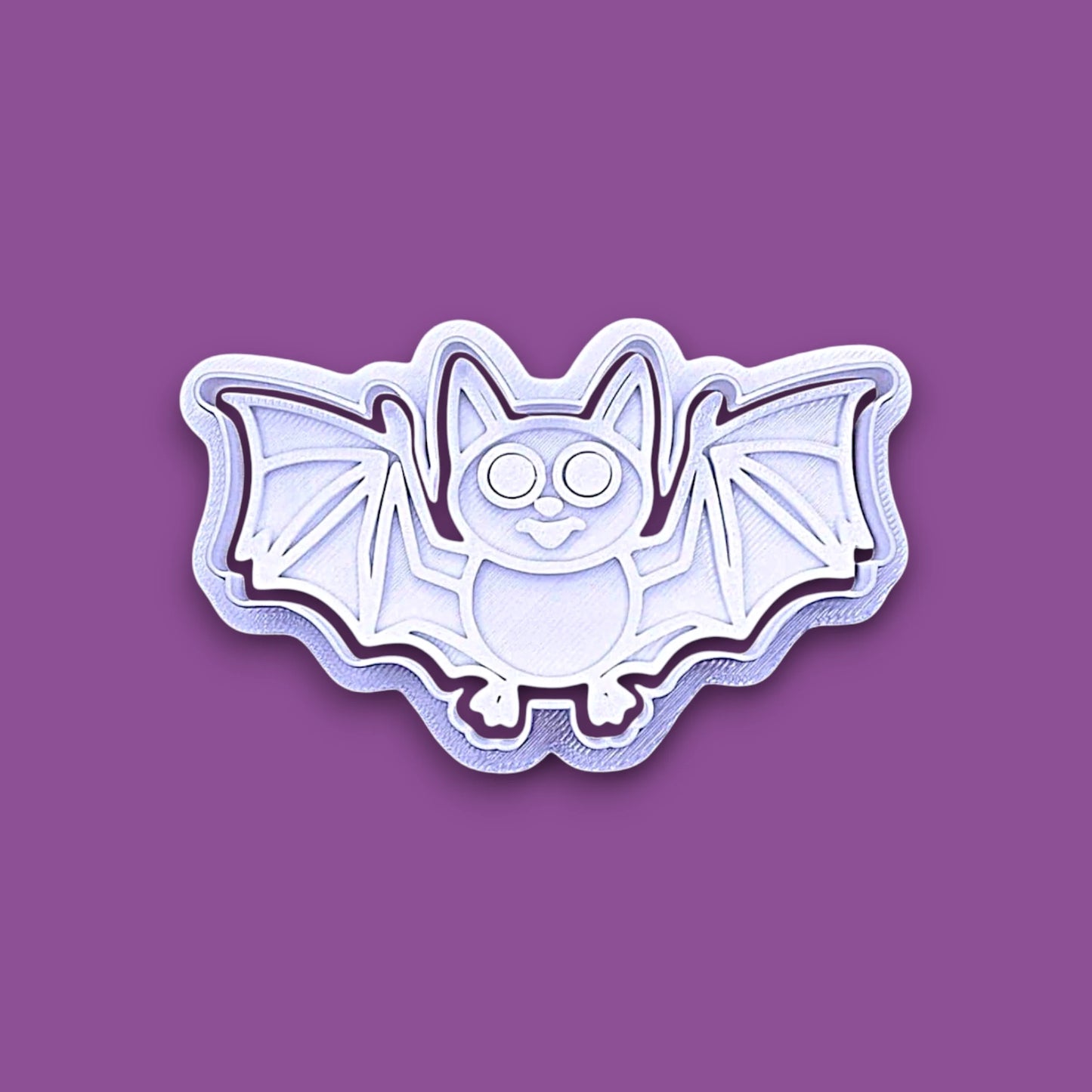 Halloween bat shaped cookie cutter and stamp shown on a purple background.