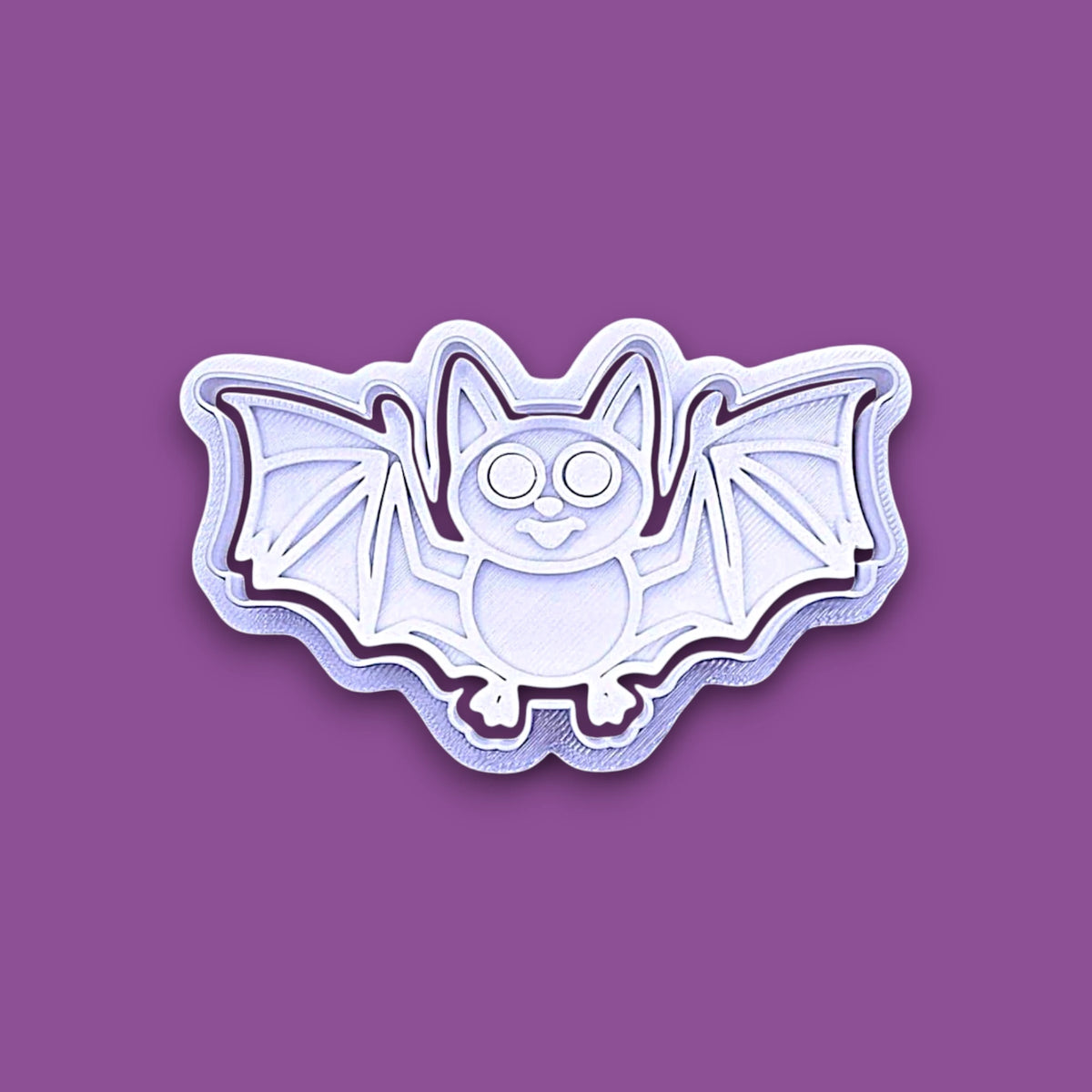 Halloween bat shaped cookie cutter and stamp shown on a purple background.