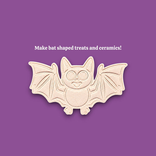 A bat-shaped cookie cutter ceramic mold centered on a solid purple background, with the text 'Make bat shaped treats and ceramics!' above it.