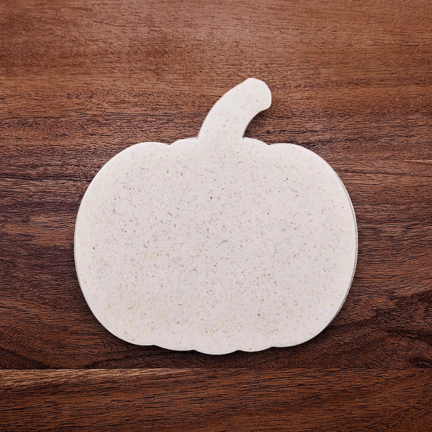 Freshly cut pumpkin-shaped cookie dough using the cutter; shows clean edges and festive form, perfect for seasonal baking projects.