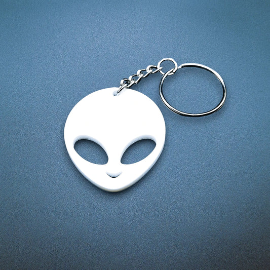 Cute alien keychain with classic UFO-style head and big eyes, front-facing, shown in vibrant white color with keyring.