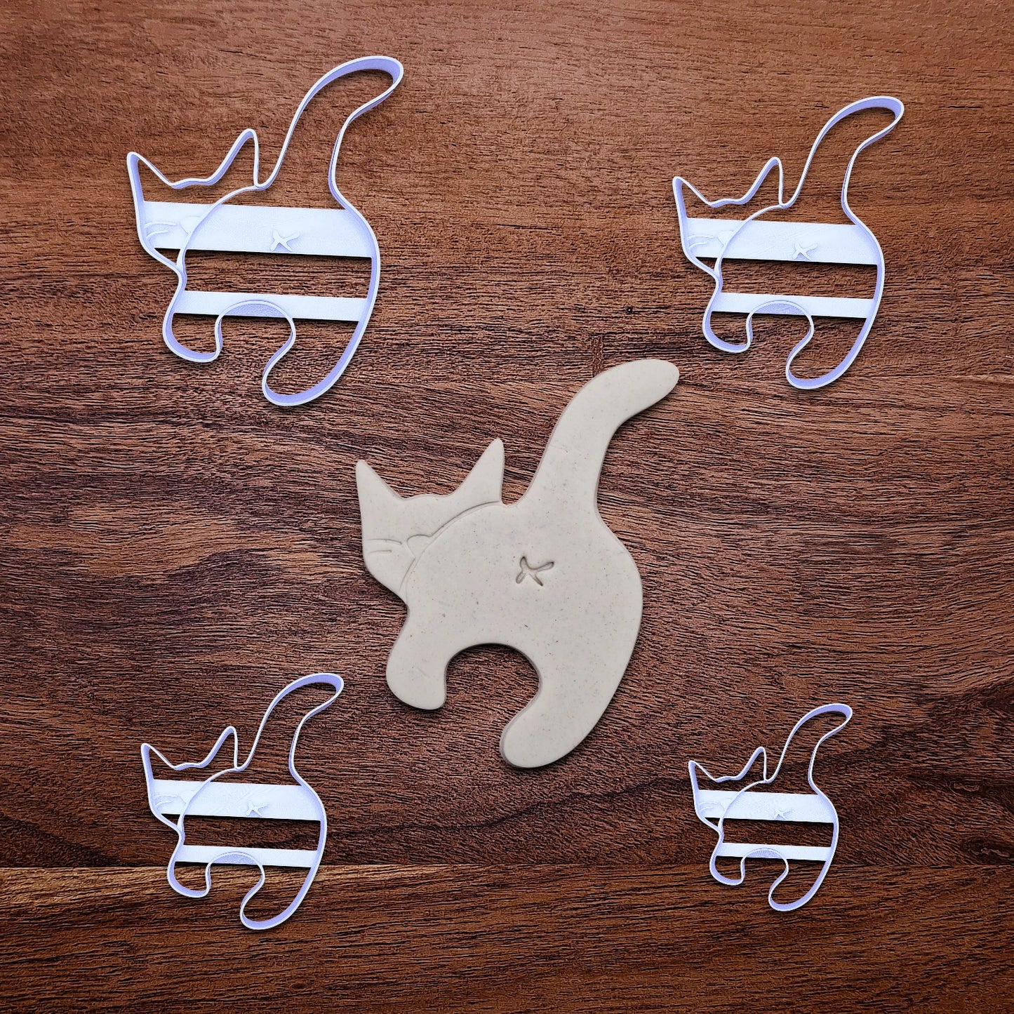 Multiple handmade and customizable cat butt cookie cutters alongside a dough cutout and imprint, perfect for gifting, gag gifts, white elephant gifting, and cat themed parties and treats.