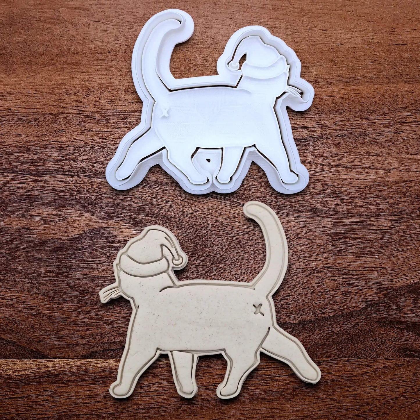 Funny Santa Hat Cat Butt Cookie Cutter and Stamp alongside a cat butt dough cutout and imprint, available in a 3-piece set or individual sizes, perfect for baking, fondant, crafts, gag gifts and white elephant parties.