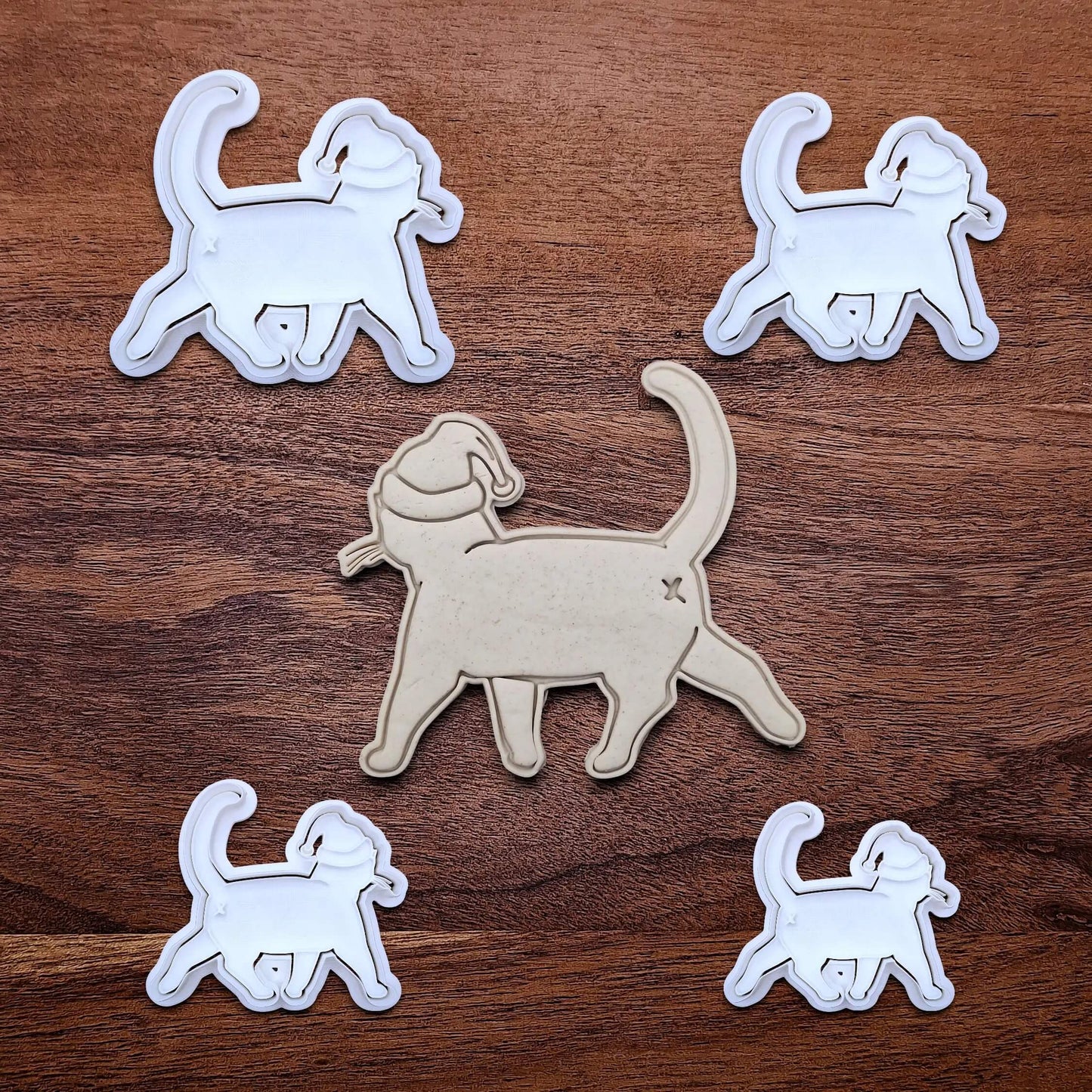 Funny Santa Hat Cat Butt Cookie Cutters and Stamps alongside a cat butt dough cutout and imprint, available in a 3-piece set or individual sizes, perfect for baking, fondant, crafts, gag gifts and white elephant parties.