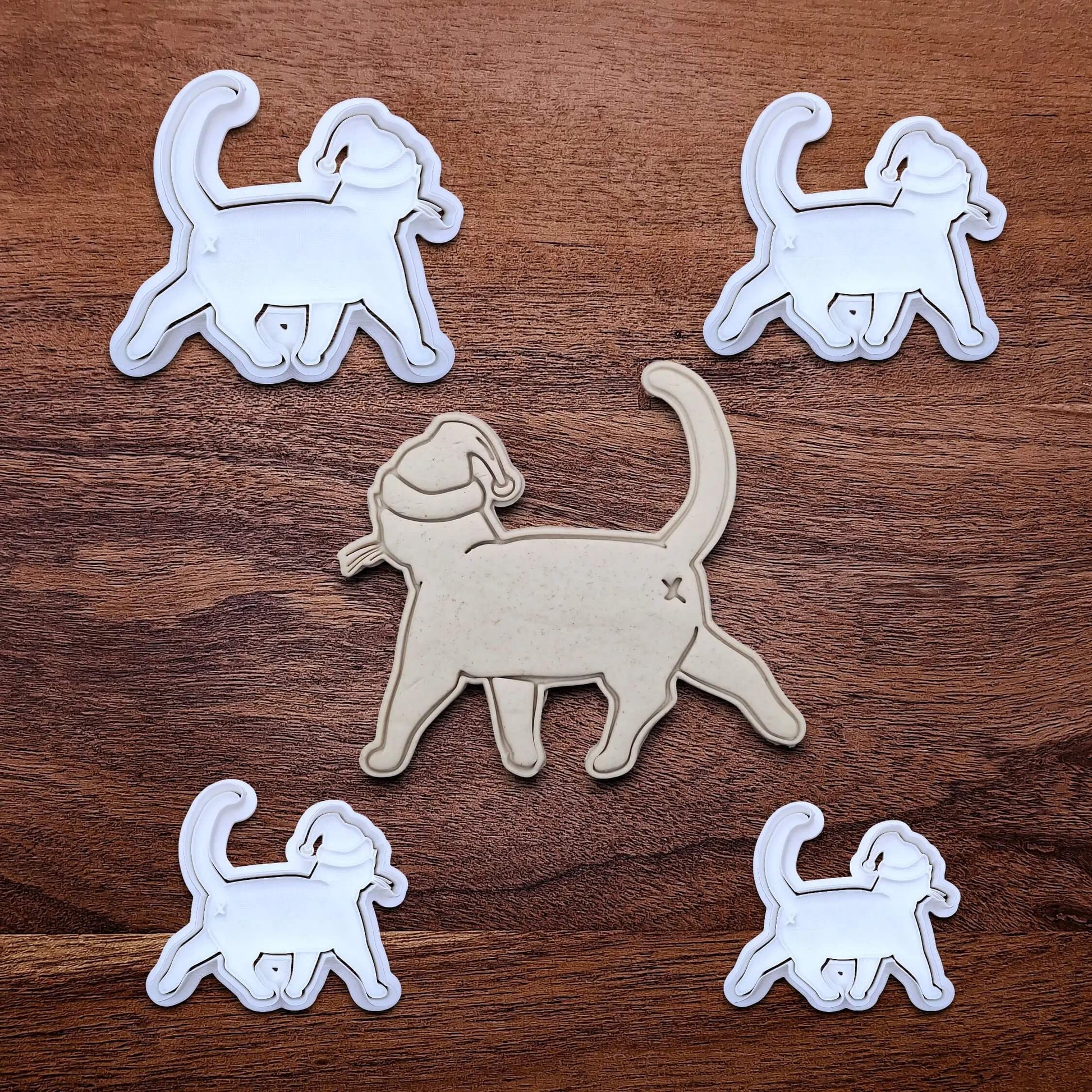Funny Santa Hat Cat Butt Cookie Cutters and Stamps alongside a cat butt dough cutout and imprint, available in a 3-piece set or individual sizes, perfect for baking, fondant, crafts, gag gifts and white elephant parties.