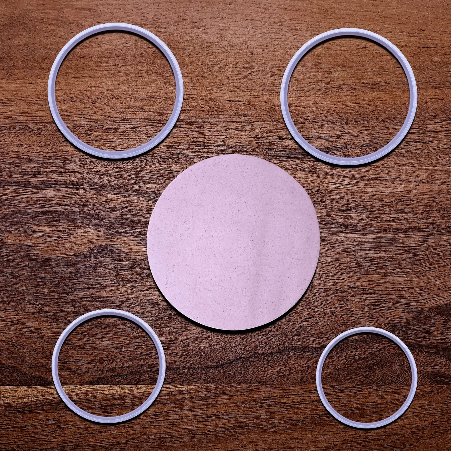 Four circle cookie cutters alongside a round dough cutout,
