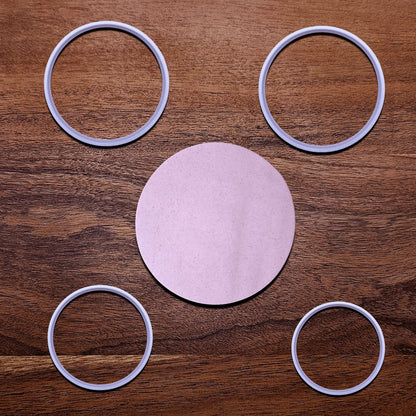 Four circle cookie cutters alongside a round dough cutout,