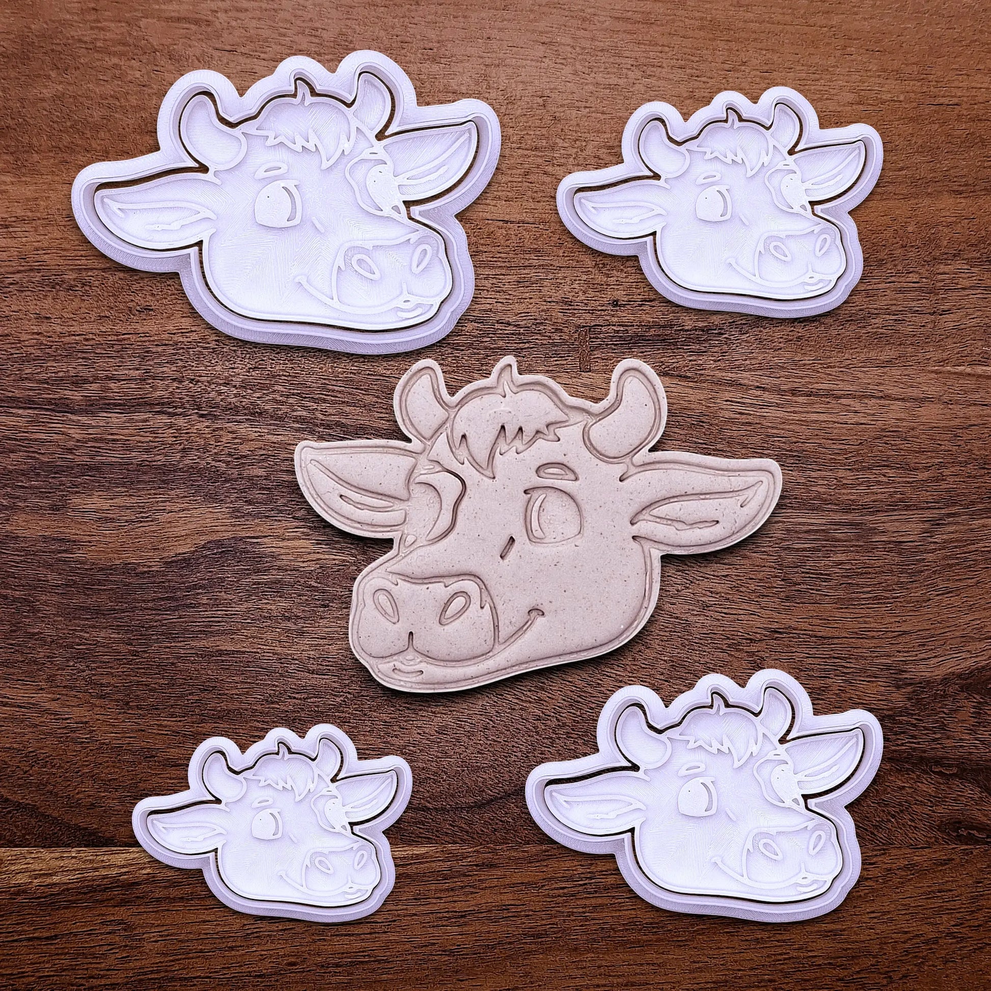 Handmade and customizable cow cookie cutters and stamps alongside a cow dough cutout and imprint, perfect for farm-themed baking and kids’ country birthday party treats.
