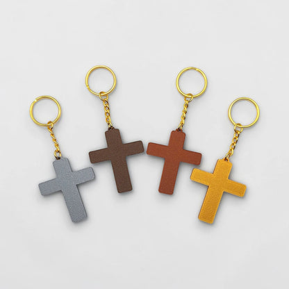 Four cross-shaped keychains in gray, brown, red, and yellow on a light gray background.