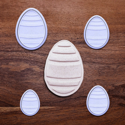 Handmade and customizable Easter egg cookie cutters and stamps alongside an egg shaped cookie cutout and imprint, perfect for Easter celebrations, spring parties, and birthday treats.