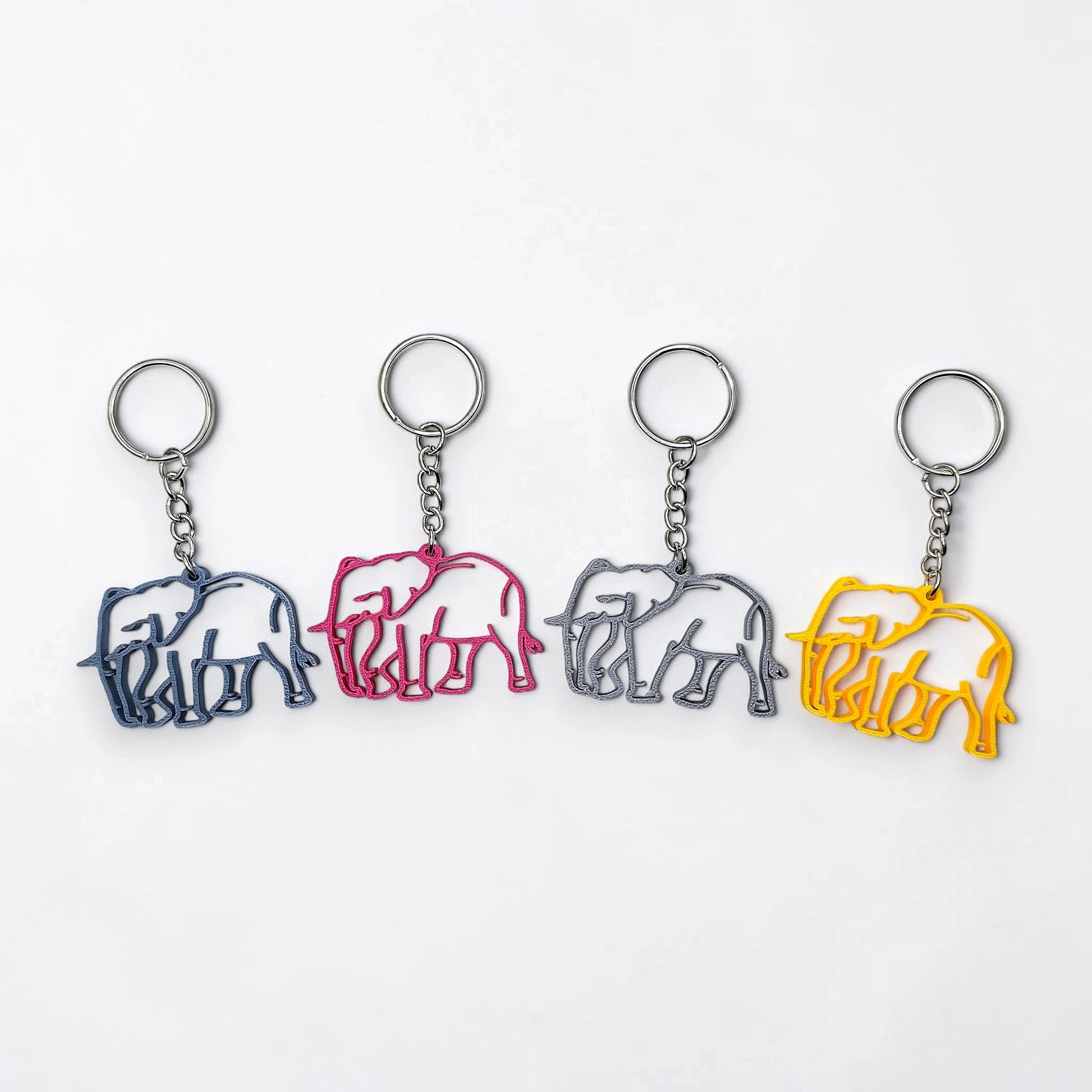 Four elephant-shaped keychains in different colors on a white background