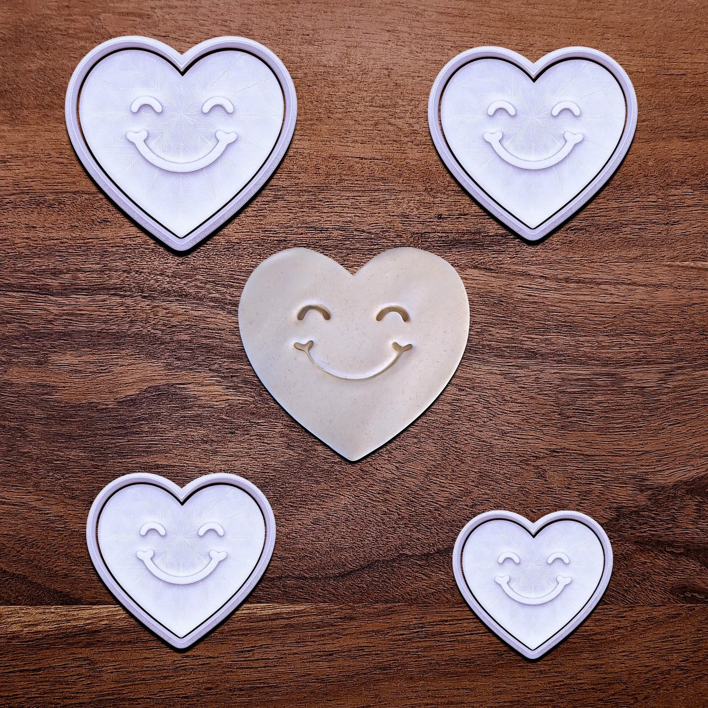 Handmade and customizable heart cookie cutters and stamps with cute face stamp alongside a dough cutout and imprint, perfect for Valentine's Day baking, sweet treats and party favor creations.