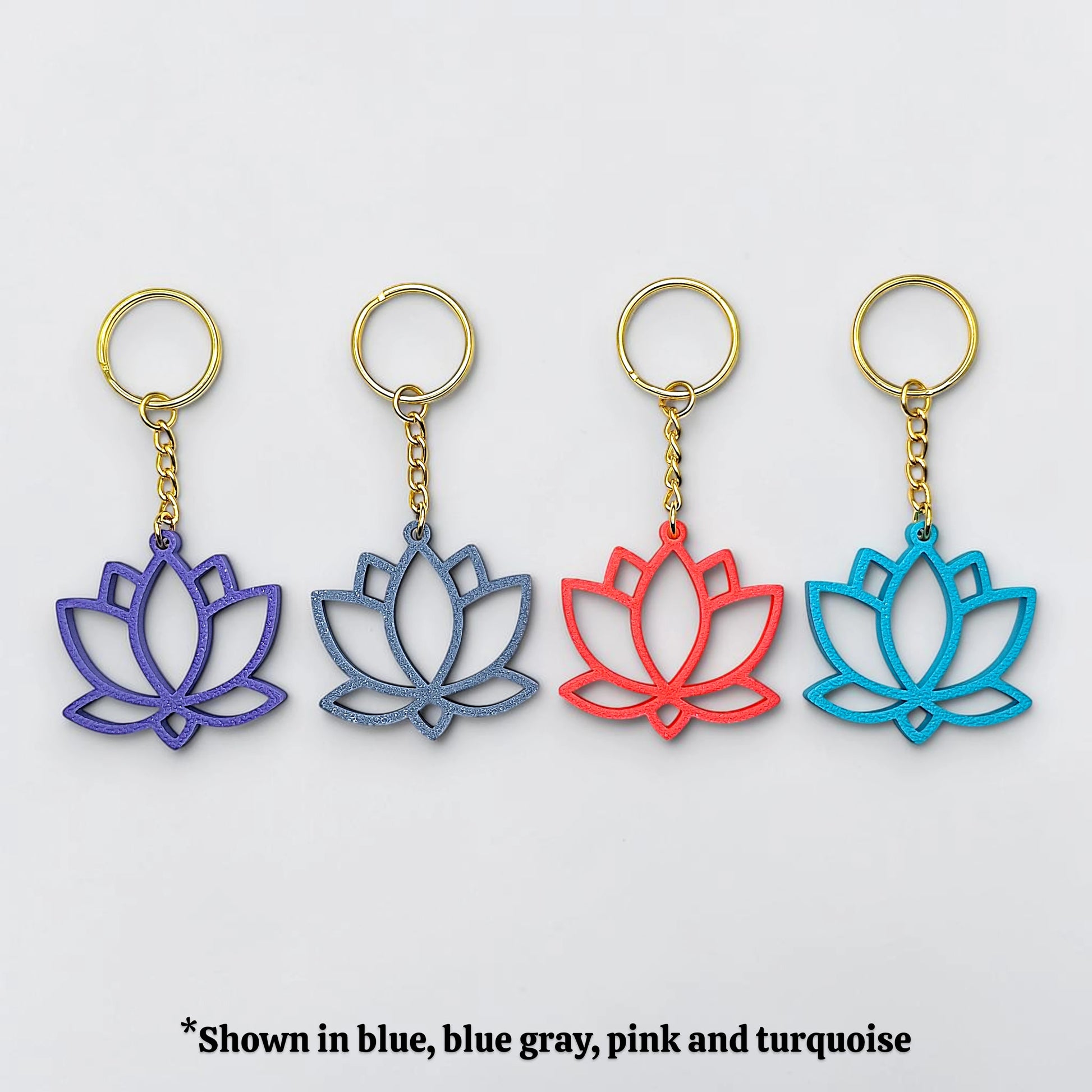 Four lotus flower keychains in blue, blue gray, pink, and turquoise on a white background.