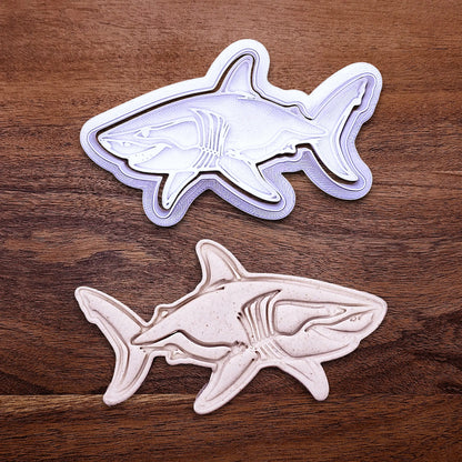 Handmade and customizable shark cookie cutter and stamp alongside a dough cutout and imprint, great for beach themed baking, fondant crafts, or ocean-themed cookies.