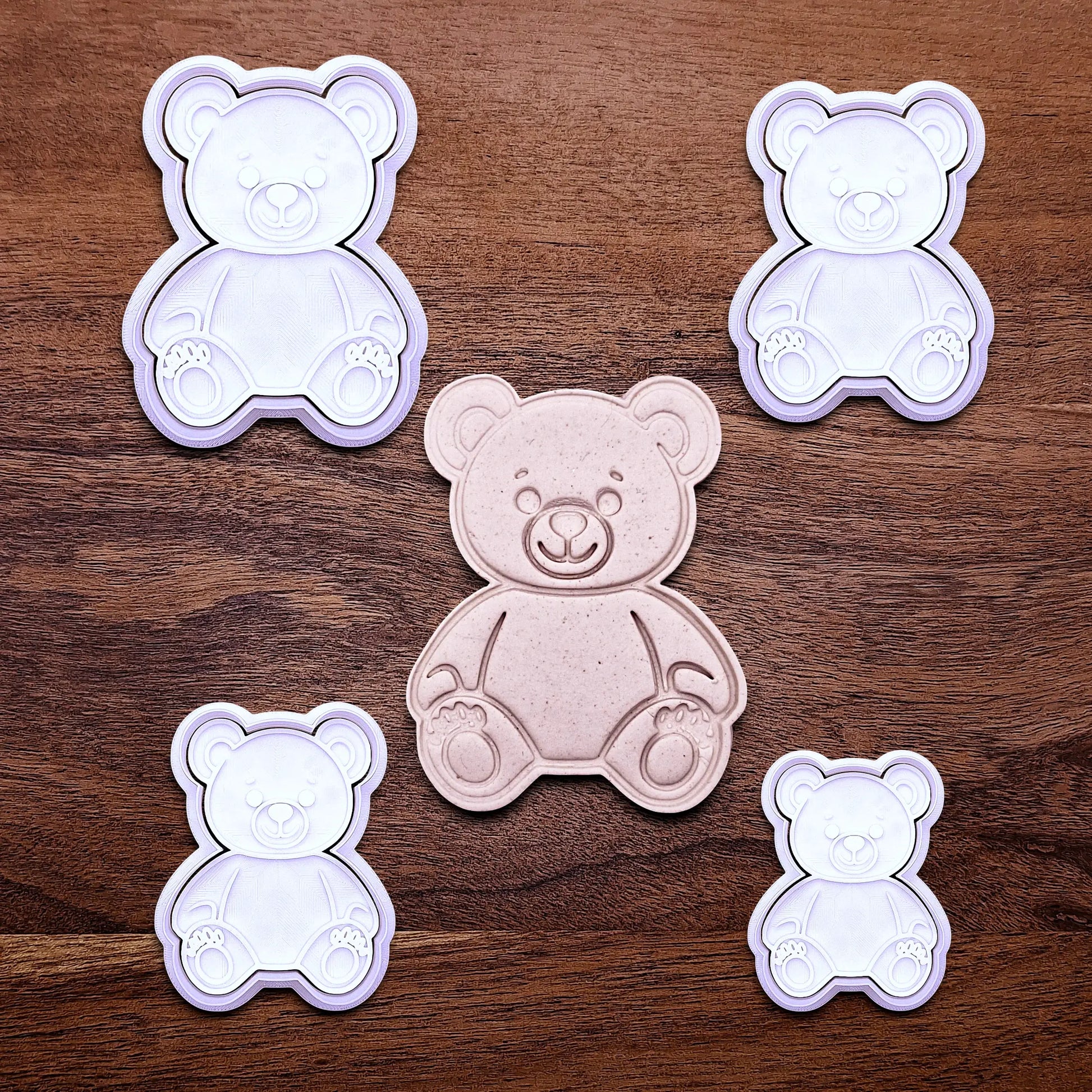 Multiple handmade and customizable teddy bear cookie cutters with stamps featuring a traditional plush bear shape alongside a dough cutout and imprint — perfect for standout cookies at Valentine's Day parties or gifting.