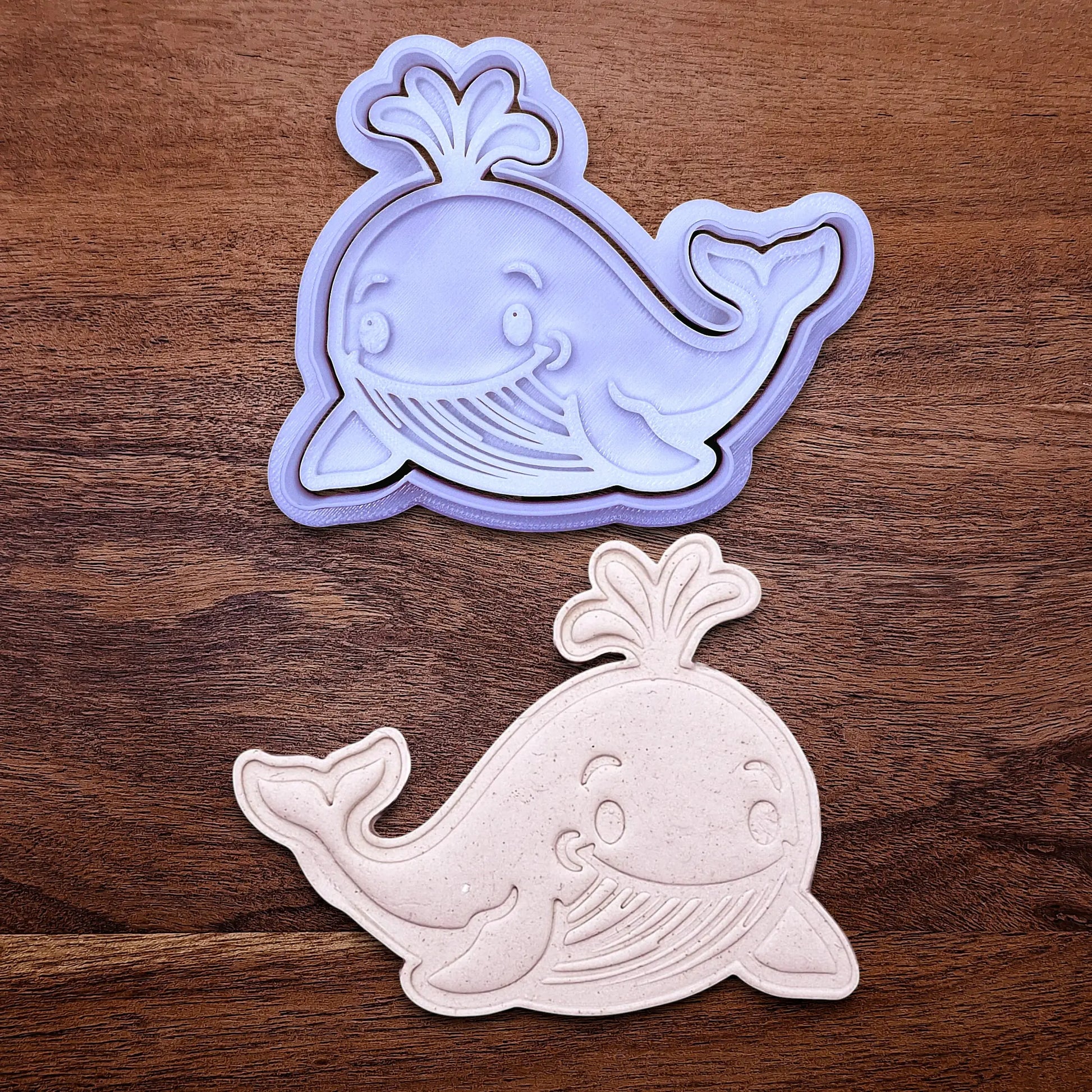 Handmade and customizable whale cookie cutter and stamp set alongside a dough cutout and imprint, ideal for making adorable aquatic and nautical cookies for baby showers, birthdays, and parties.