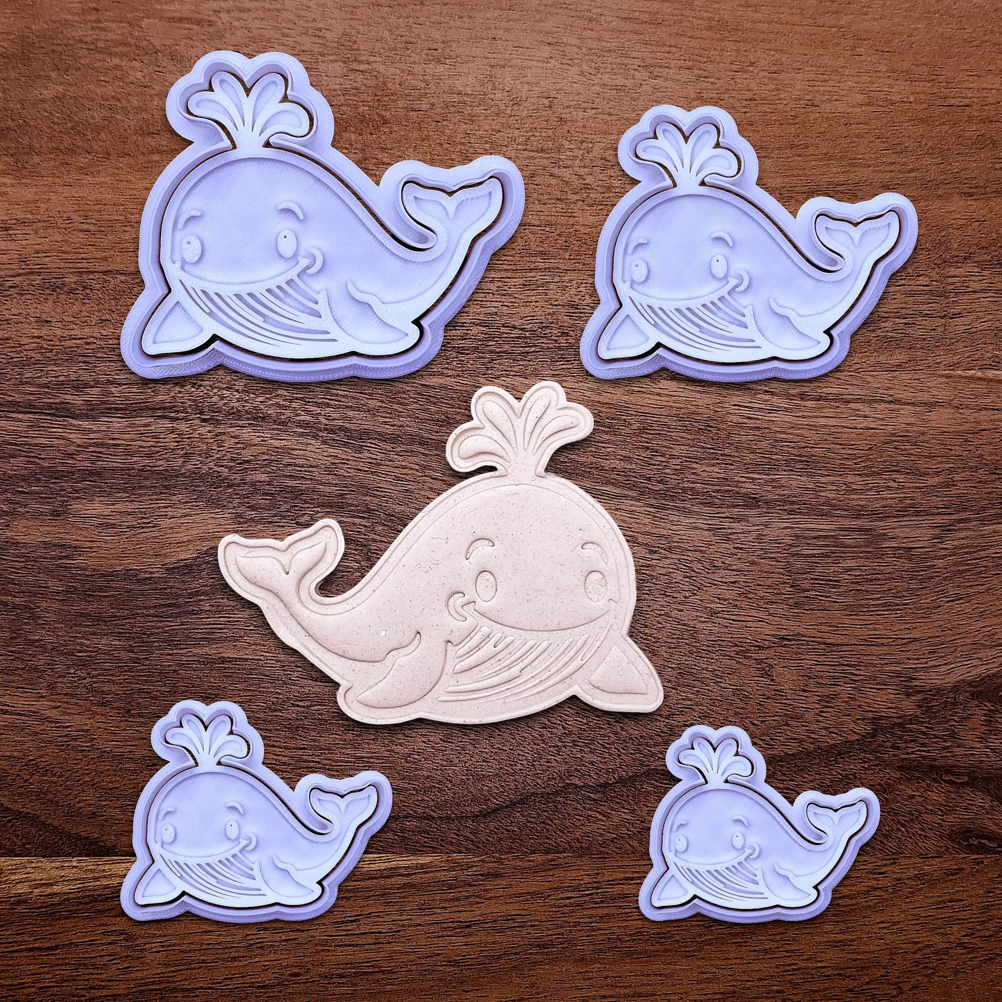 Handmade and customizable whale cookie cutters and stamps set alongside a dough cutout and imprint, ideal for making adorable aquatic and nautical cookies for baby showers, birthdays, and parties.