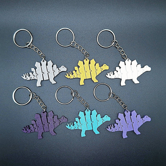 Top view of six fidget dinosaur keychains with articulated segments, ideal for sensory use, kids’ gifts, or dino-themed party favors.