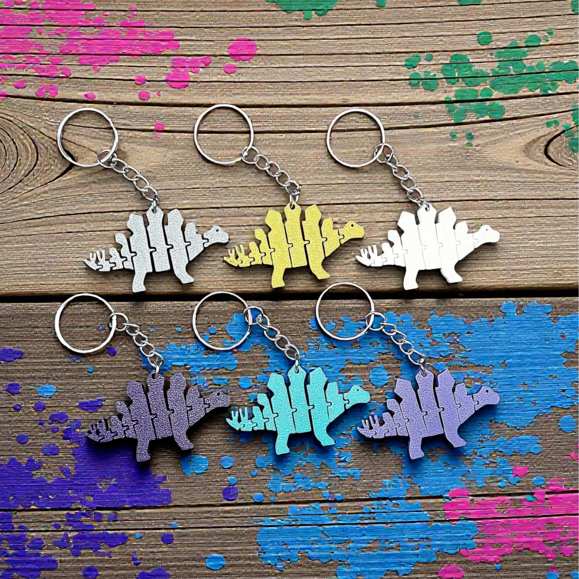 Handmade and customizable dinosaur fidget keychains in various colors, featuring colorful articulated designs, perfect for kids birthday parties, classroom prizes, sensory play, and party favor dino gifts.
