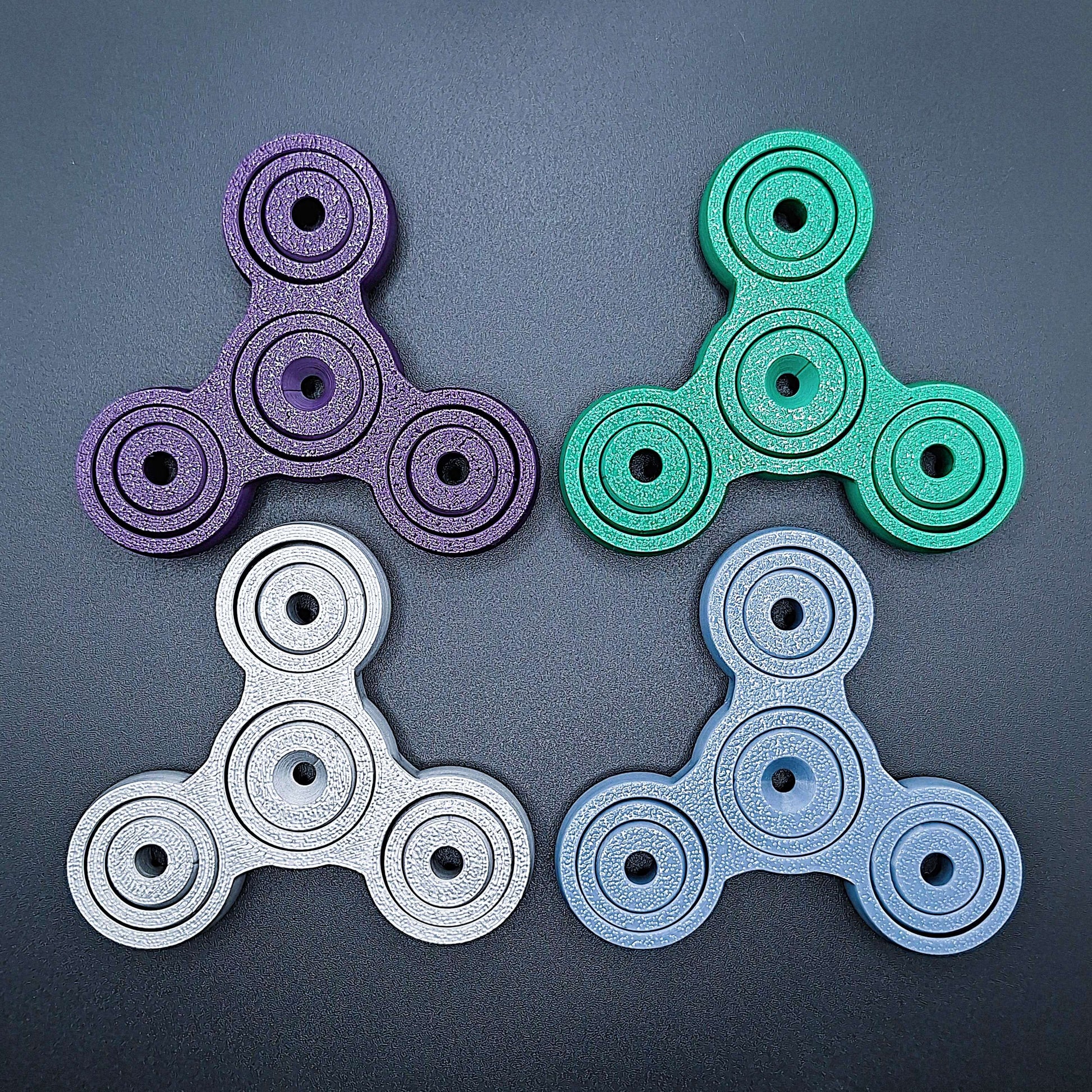 Colorful 3" pronged fidget gyro spinners in four colors—perfect stress relief tool for focus, anxiety, and sensory play. Eco-friendly, handmade.
