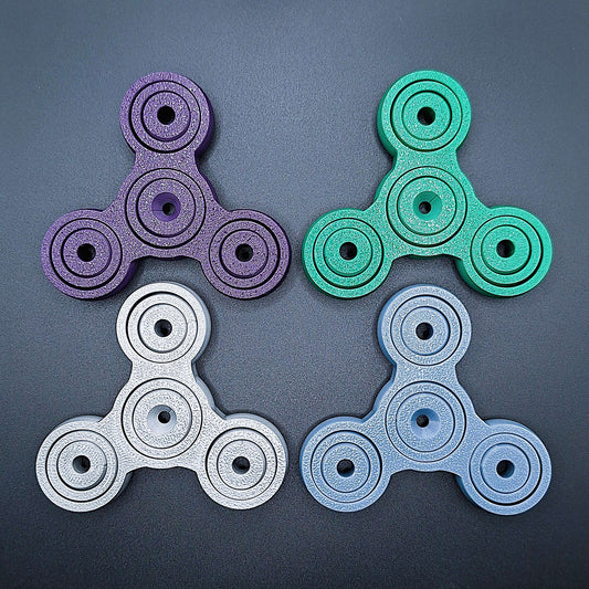 Colorful 3" pronged fidget gyro spinners in four colors—perfect stress relief tool for focus, anxiety, and sensory play. Eco-friendly, handmade.