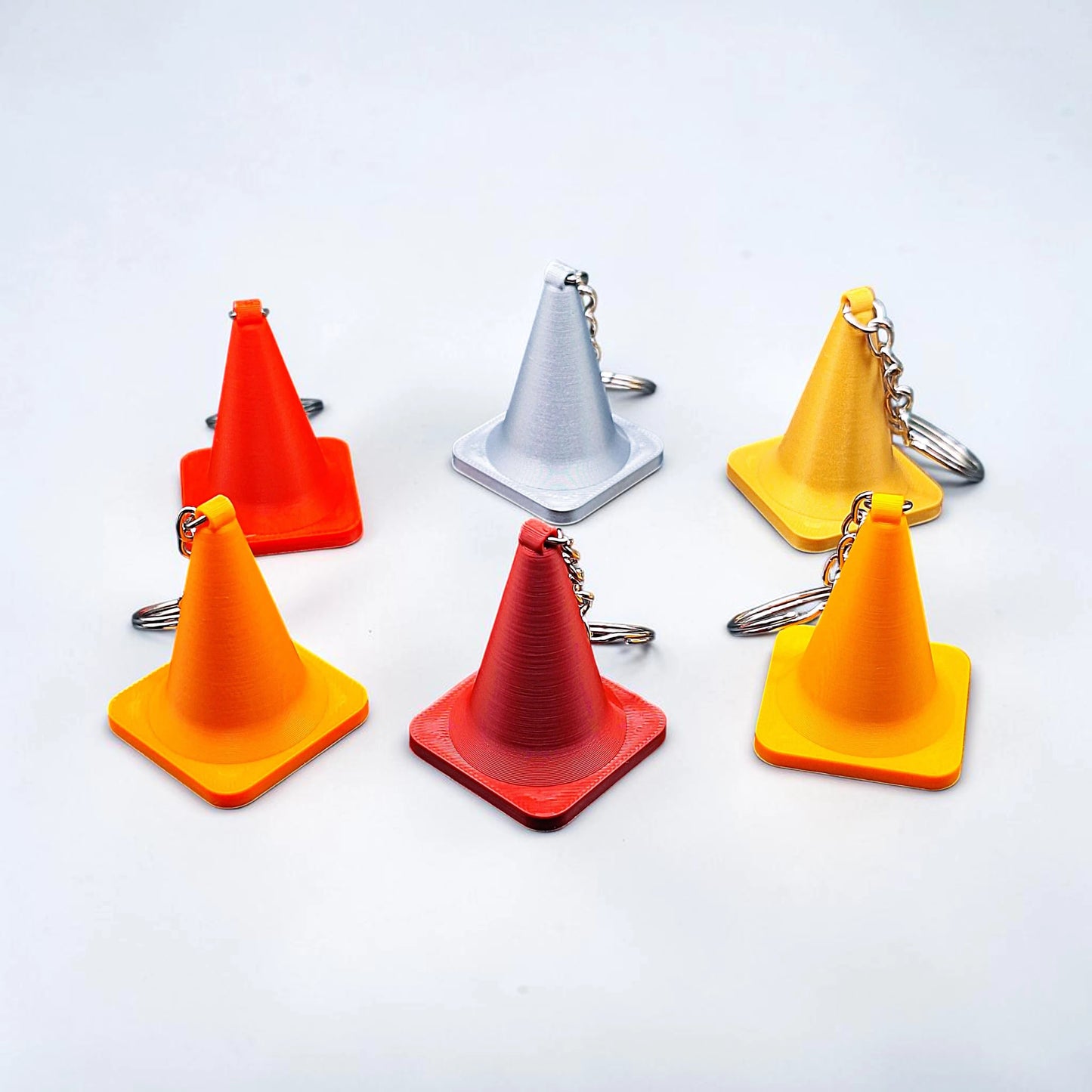 Six traffic cone keychains in various colors, handmade from biodegradable PLA plastic, perfect for engineers, drivers, or novelty gifts.