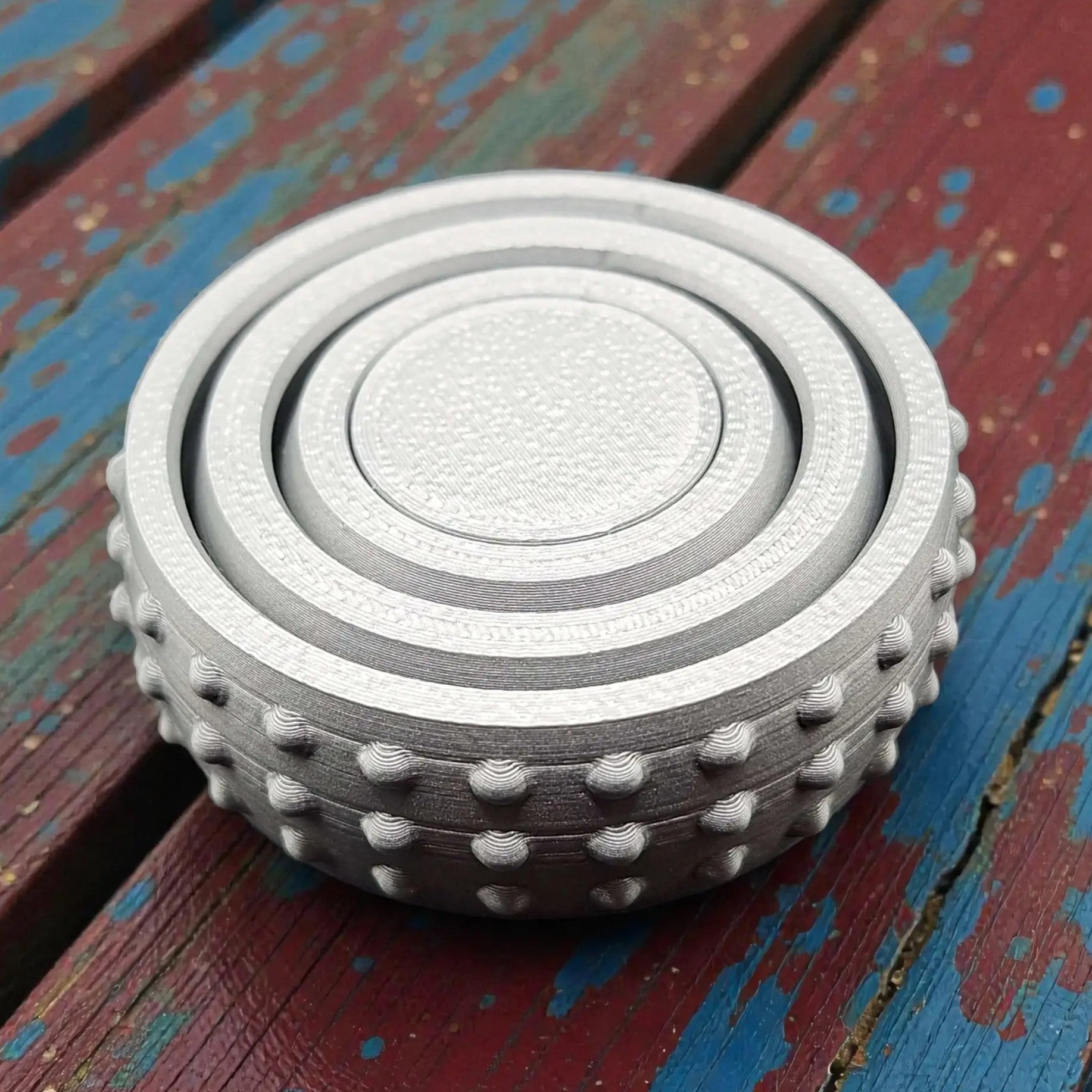 Front view of silver pocket-sized fidget spinner, minimal and modern design made from plant-based plastic for portable stress relief.
