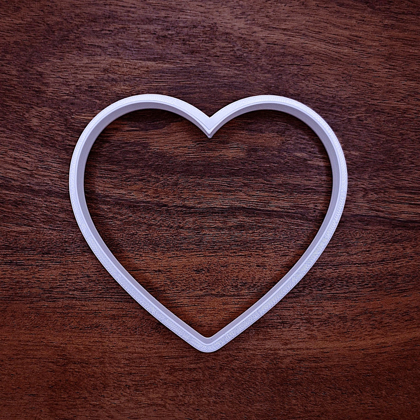 Heart-shaped baking cutter with smiley face imprint, great for cookies, cake toppers, fondant, crafts, and DIY holiday treats.