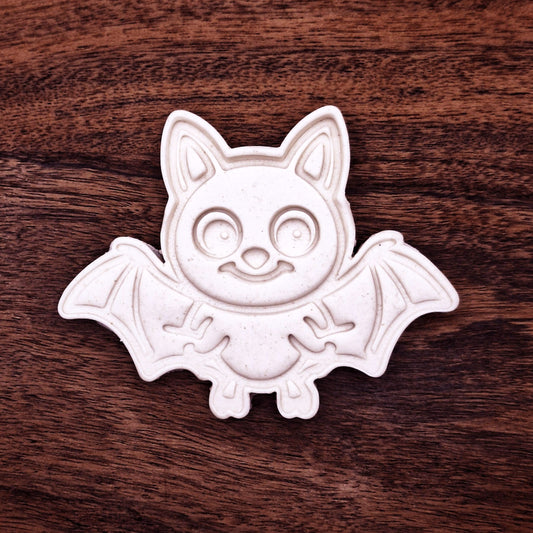 Dough cutout with bat design pressed by cutter and stamp set, showing detailed lines—great for easy Halloween cookie decorating without icing.