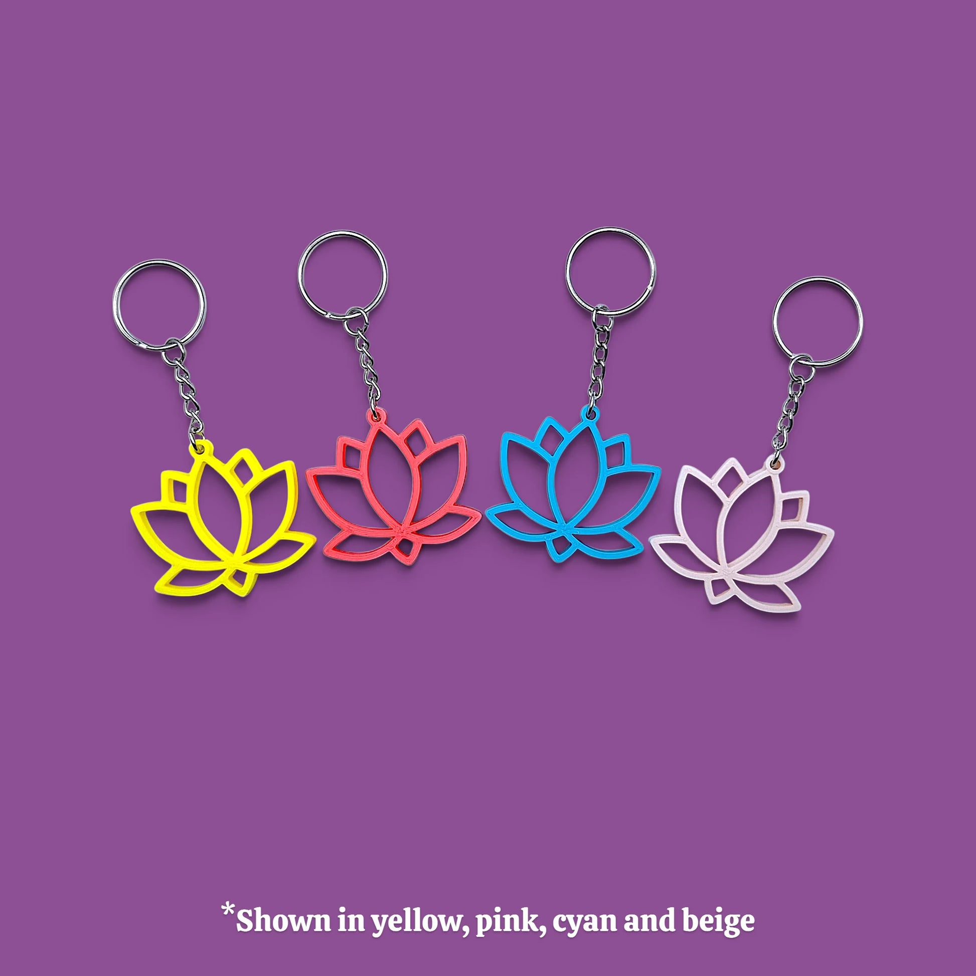 Four lotus-shaped keychains in different colors (yellow, pink, cyan, and beige) arranged horizontally on a solid purple background, with a text overlay at the bottom stating '*Shown in yellow, pink, cyan and beige'.