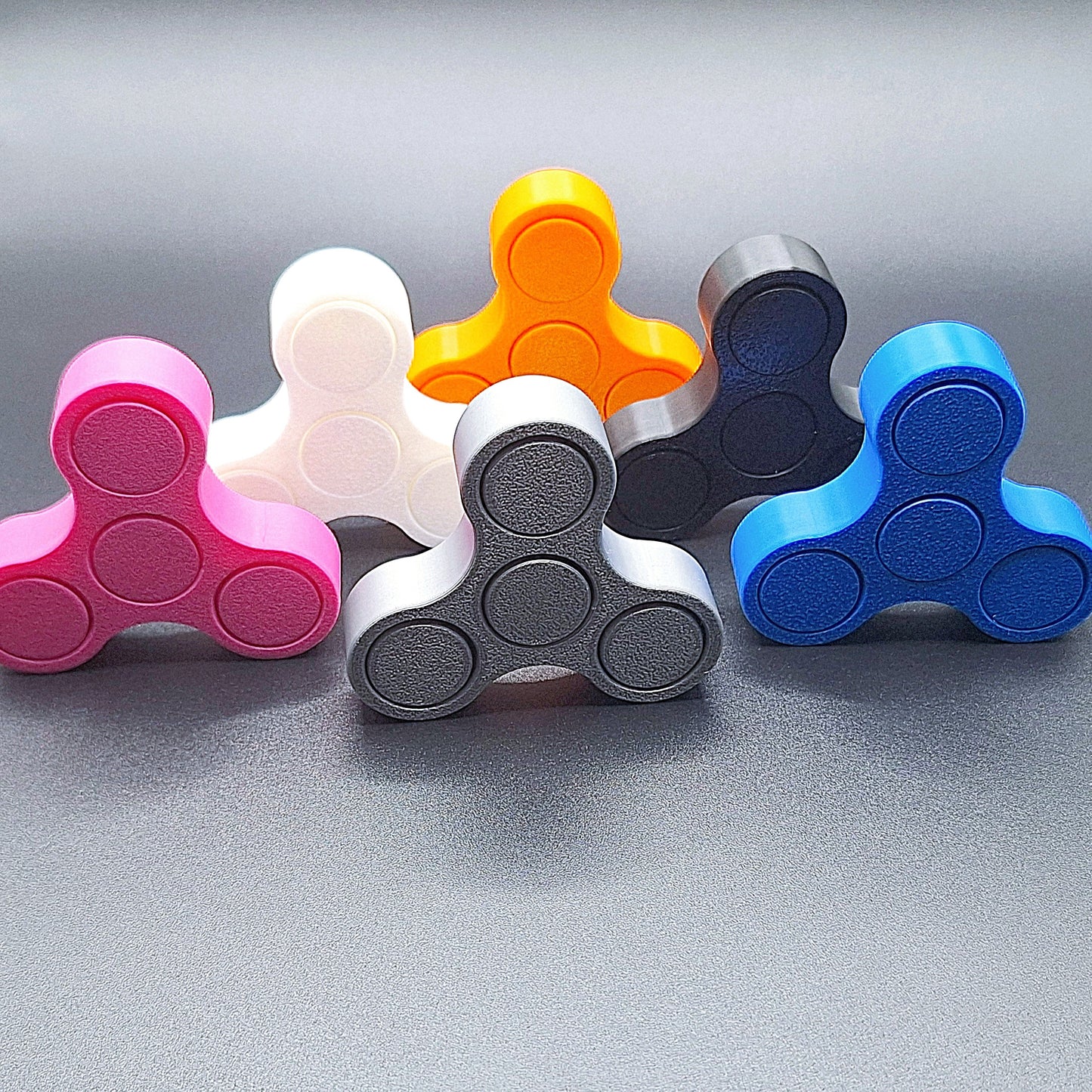 Six mini fidget spinners shown against a black background, handmade in vibrant colors and ideal for quiet, stress-relieving play and focus.