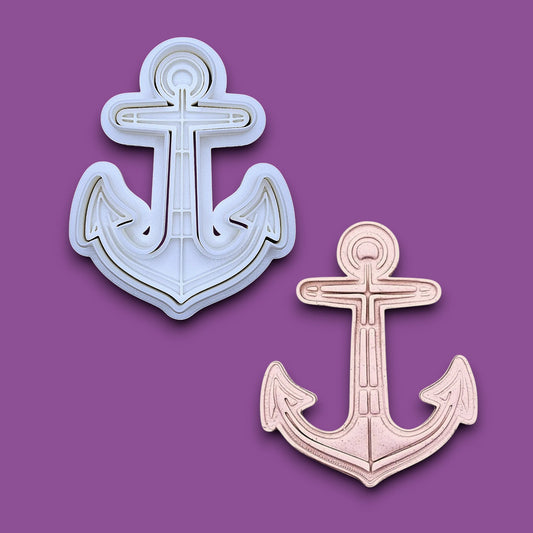 A white plastic anchor-shaped baking and craft cookie cutter, alongside a smaller matching anchor-shaped dough cutout and imprint.