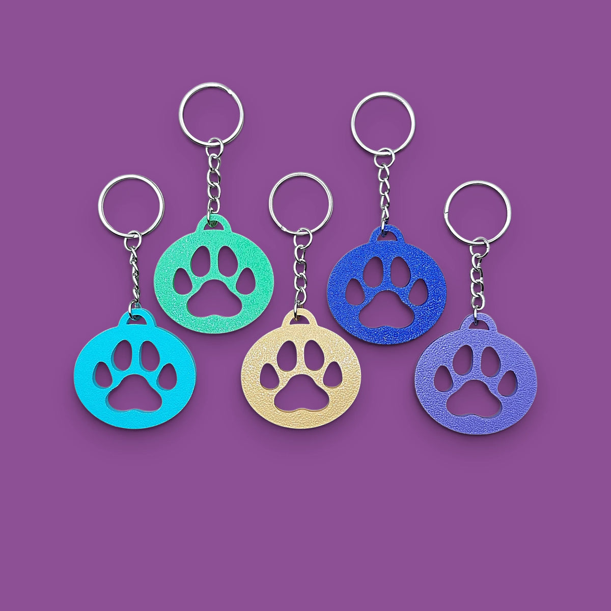 Paw print keychains in assorted colors, perfect for dog moms, cat lovers, rescue volunteers, shelter giveaways, and vet clinics. Handmade and customizable in 30 unique colors.