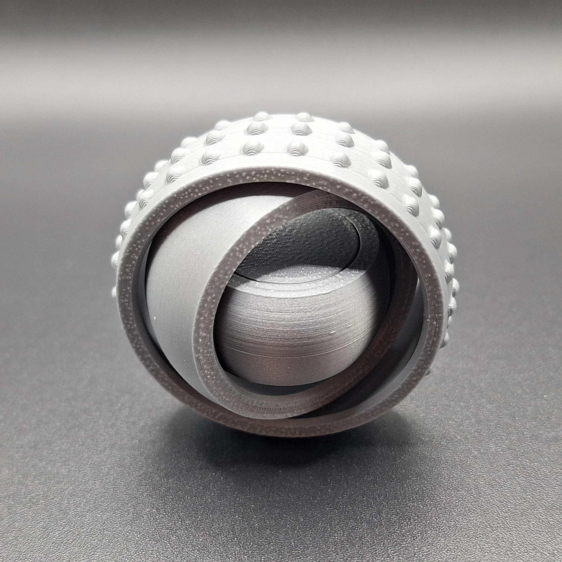 Front view of silver pocket-sized fidget spinner, minimal and modern design made from plant-based plastic for portable stress relief.