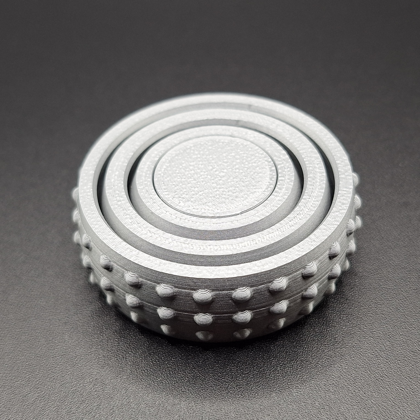 Top angle of a silver mini fidget gyro spinner, showcasing its sleek build and smooth finish—ideal for desks, bags, or pockets.