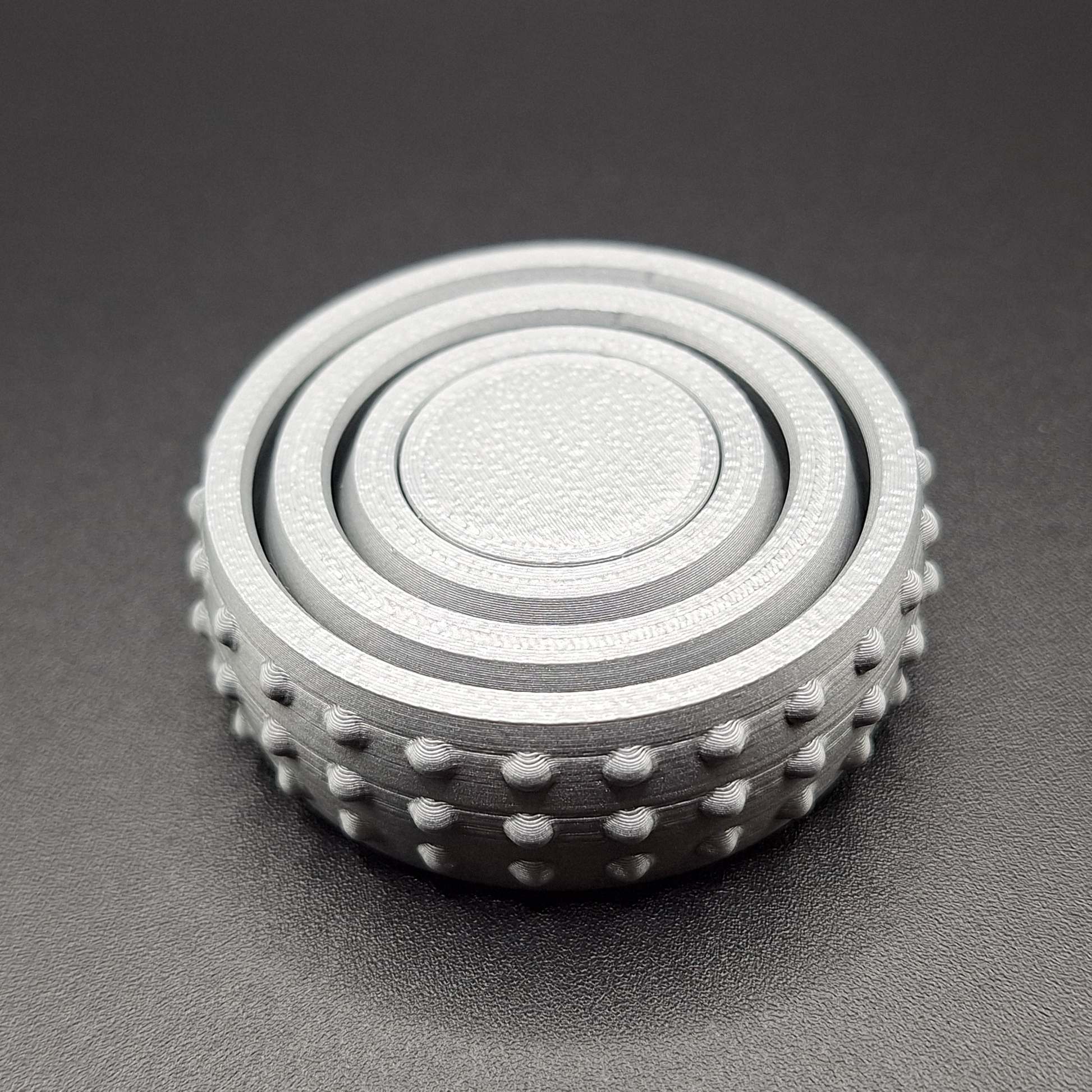 Top angle of a silver mini fidget gyro spinner, showcasing its sleek build and smooth finish—ideal for desks, bags, or pockets.