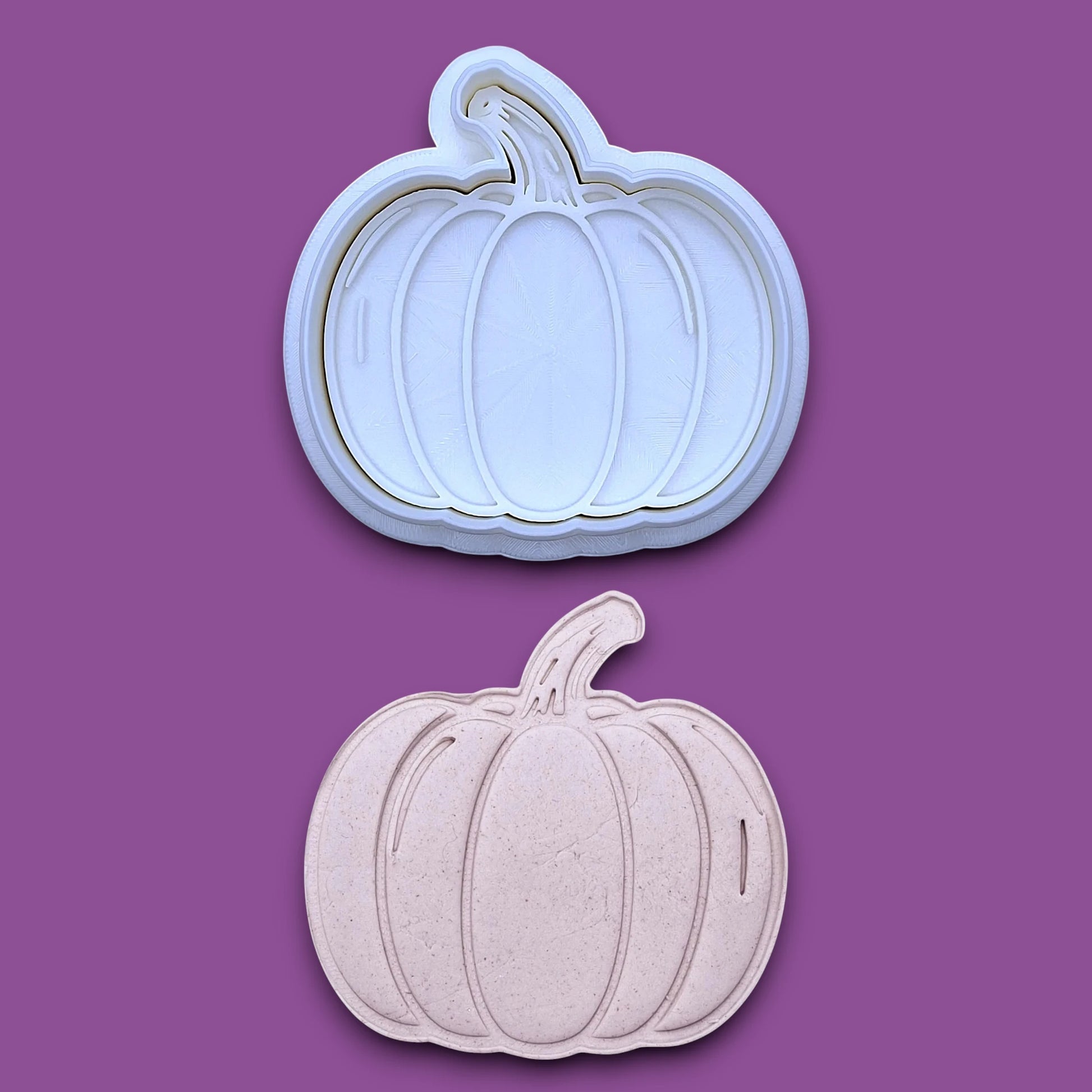 Pumpkin cookie cutter and stamp along with a pumpkin dough cutout, perfect for fall, Halloween, and Thanksgiving-themed baking or crafts.