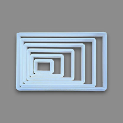 A rectangular cookie cutter set, photographed from above on a solid gray background.