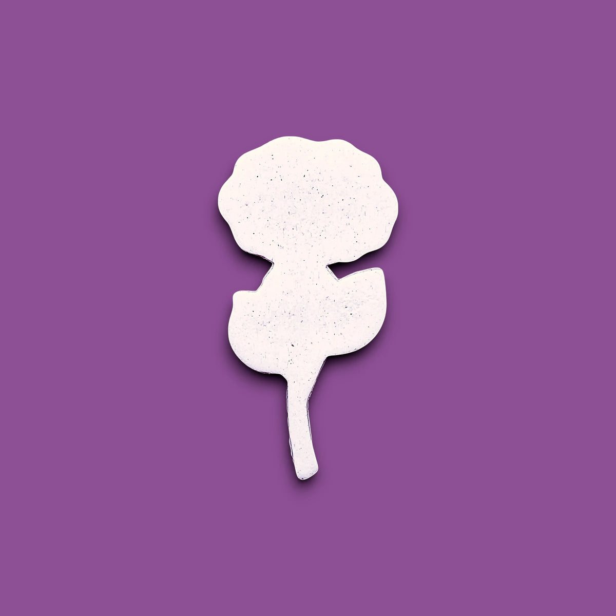 A white rose-shaped cookie cutter dough cutout is centered on a solid purple background.