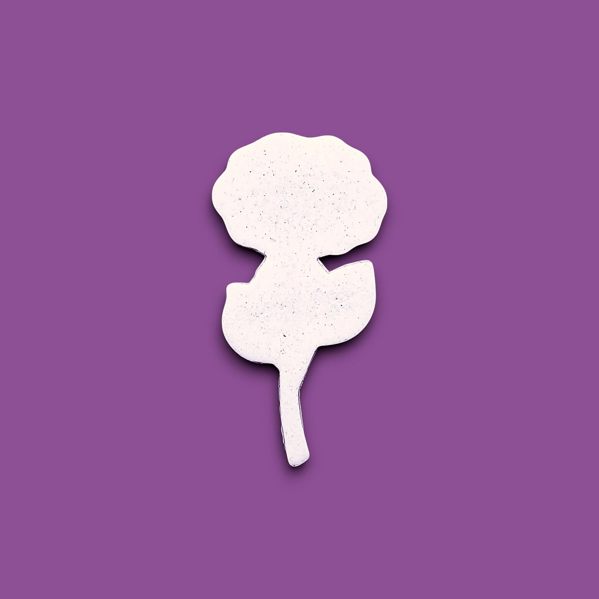 A white rose-shaped cookie cutter dough cutout is centered on a solid purple background.