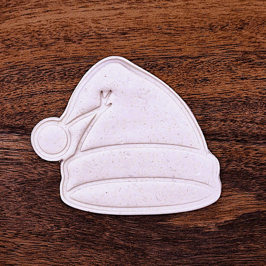 Stamped cookie dough cutouts of a Santa hat. Includes fun detail like the fluffy brim and pom-pom—great for festive treats.