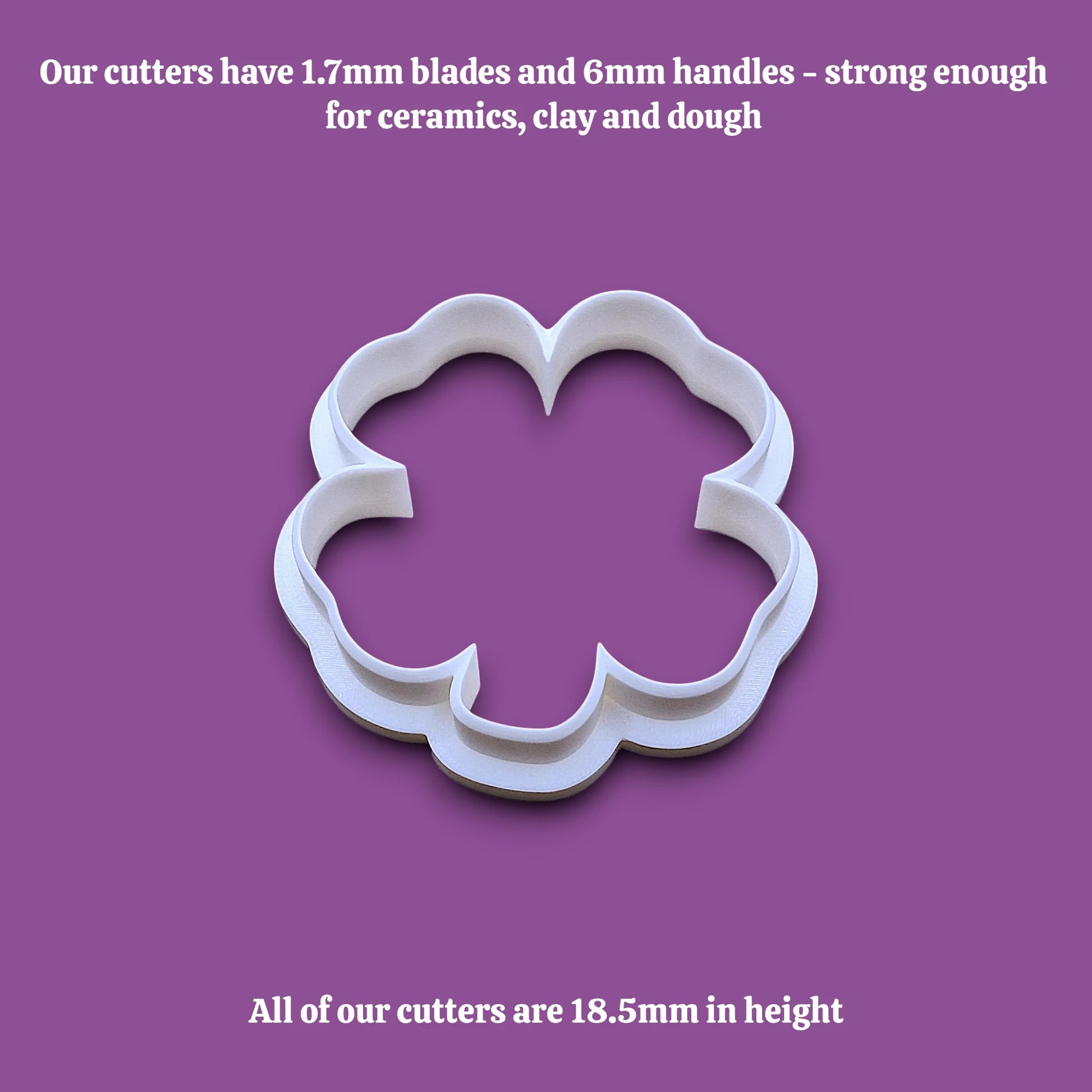 A white shamrock four leaf clover cookie cutter shown on a plain gray background with black text at the top and bottom describing the cutter's blade and handle sizes and height.