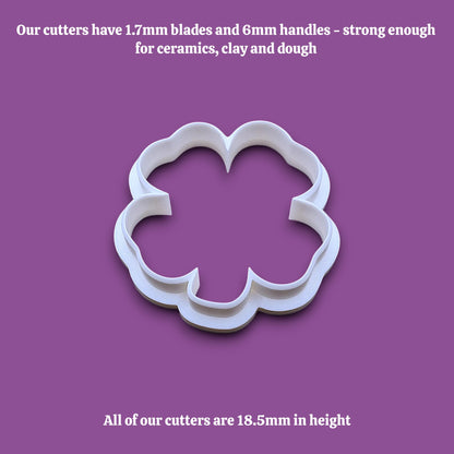 A white shamrock four leaf clover cookie cutter shown on a plain gray background with black text at the top and bottom describing the cutter's blade and handle sizes and height.