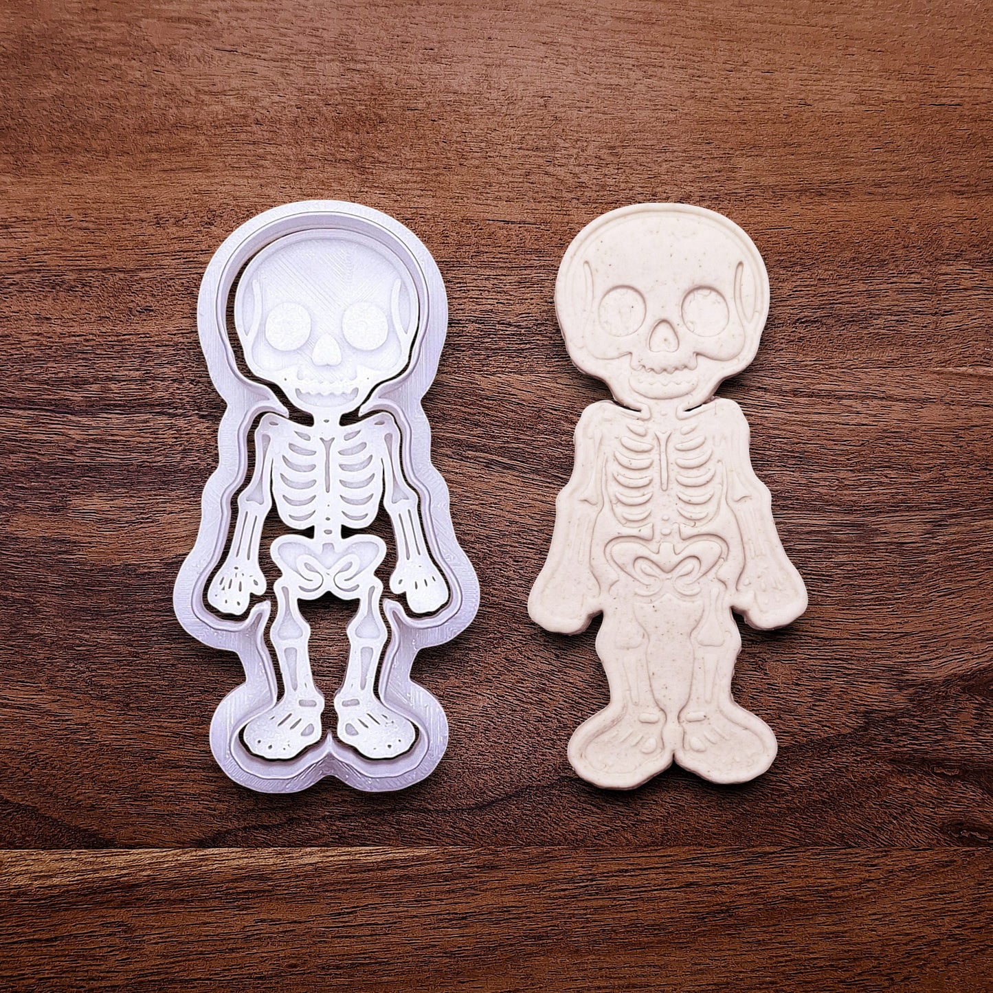 Skeleton cookie cutter stamp beside a dough imprint, perfect for outline cookies, fondant toppers, or Halloween crafts.