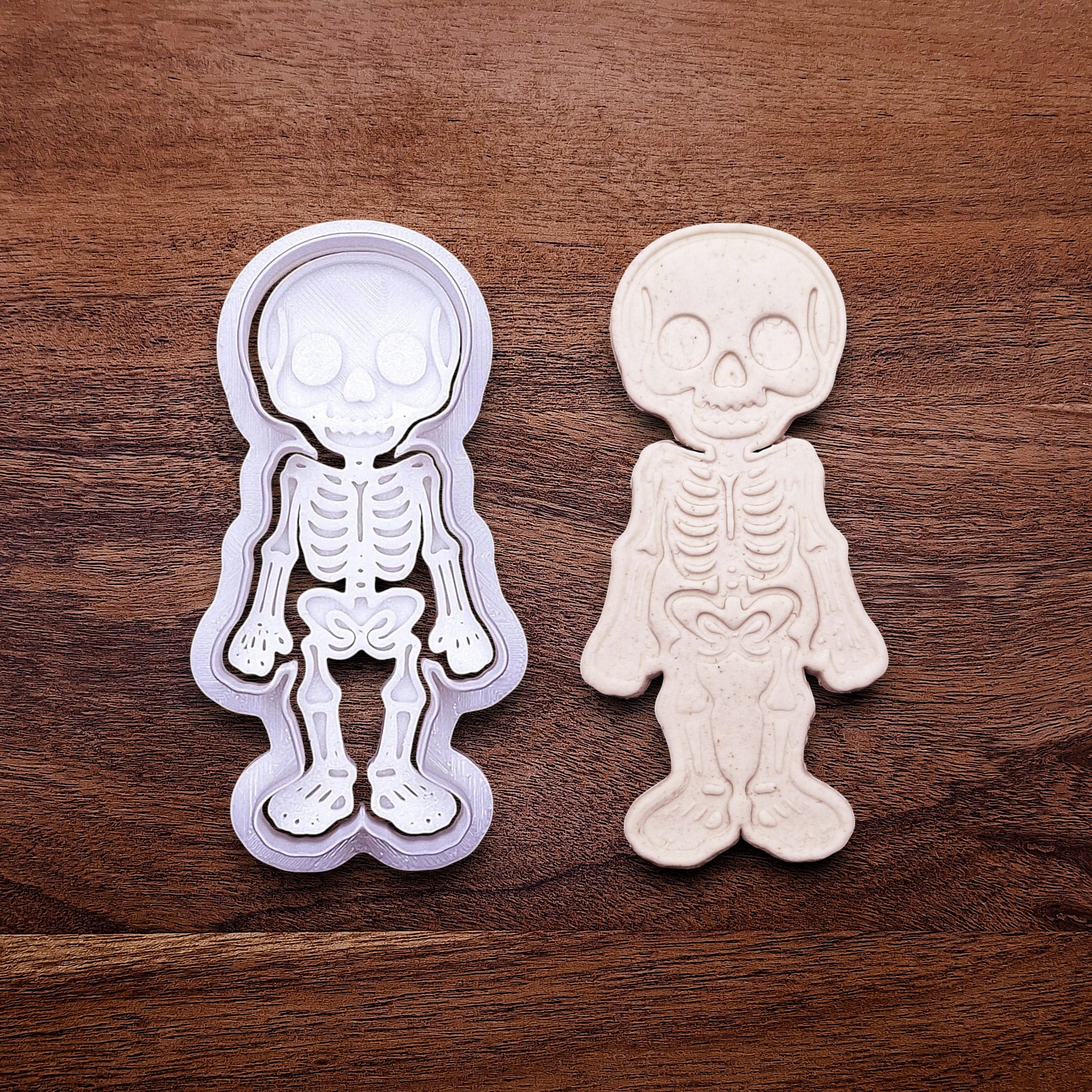 Skeleton cookie cutter stamp beside a dough imprint, perfect for outline cookies, fondant toppers, or Halloween crafts.