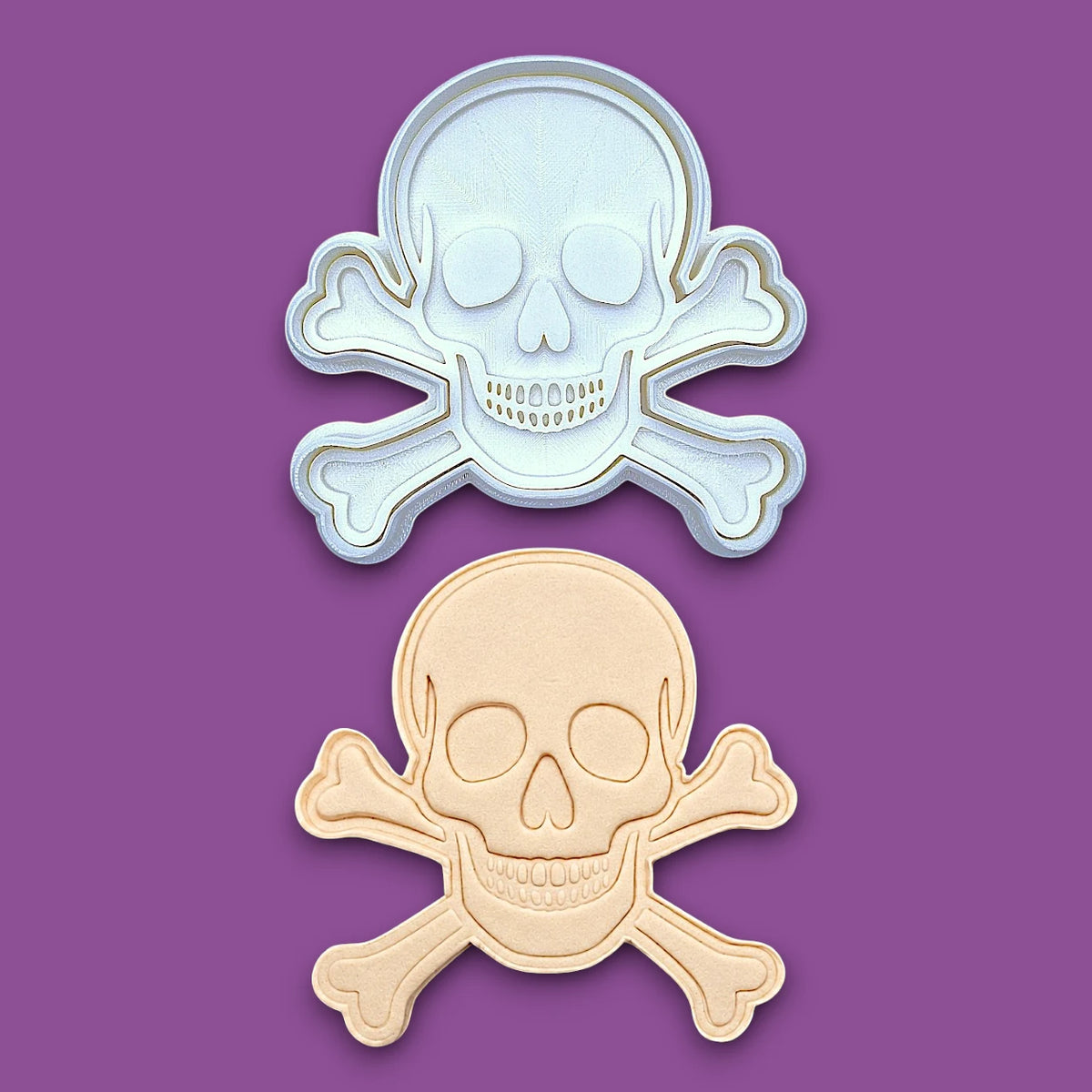 Skull and bones cookie cutter with stamp alongside a dough cutout and imprint, perfect for beach parties, Halloween treats, under the sea treats and pirate themed birthdays.