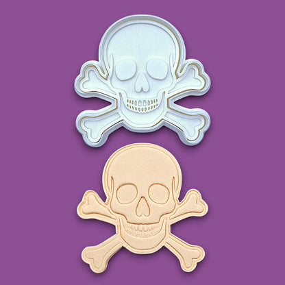 Skull and bones cookie cutter with stamp alongside a dough cutout and imprint, perfect for beach parties, Halloween treats, under the sea treats and pirate themed birthdays.