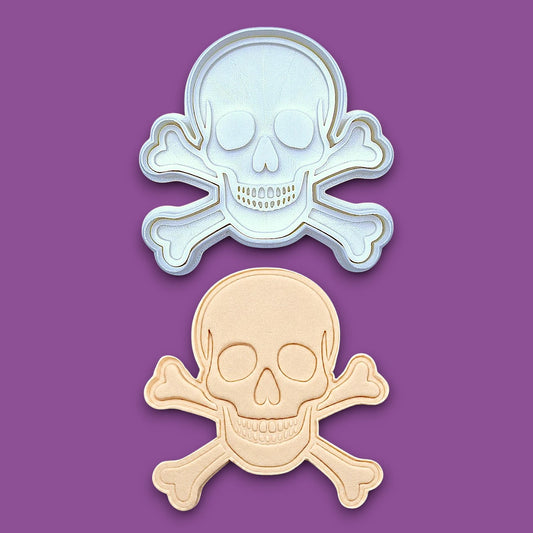 Skull and bones cookie cutter with stamp alongside a dough cutout and imprint, perfect for beach parties, Halloween treats, under the sea treats and pirate themed birthdays.