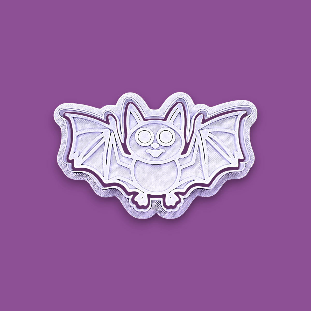 Halloween bat shaped cookie cutter and stamp shown on a purple background.