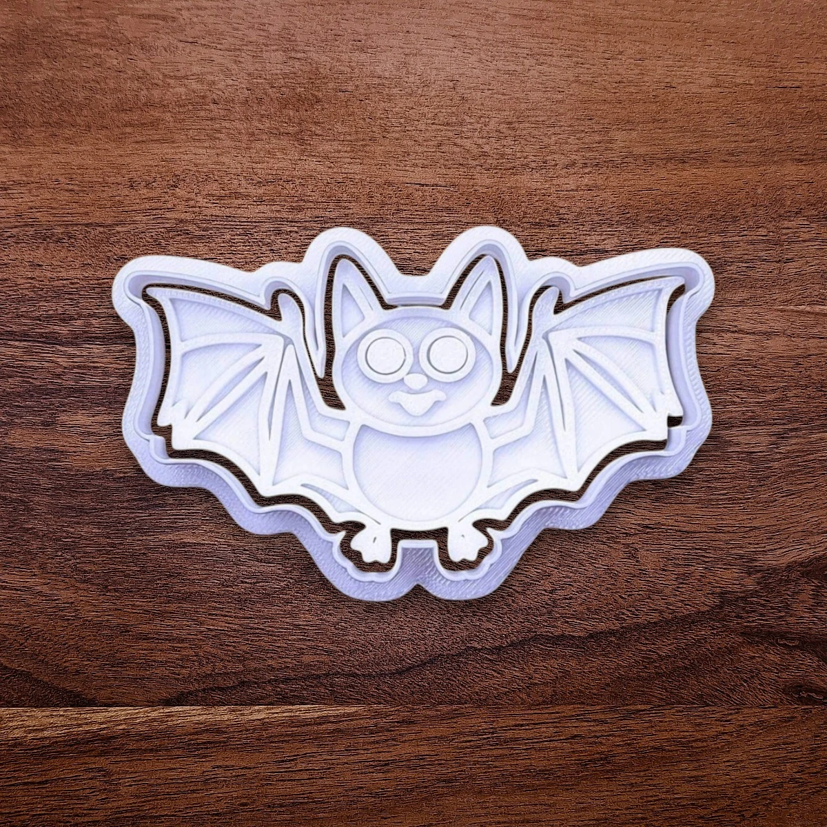 Bat-shaped Halloween cookie cutter on a wooden surface